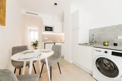 a white kitchen with a table and a washing machine at Fantastico Apartamento en Valencia in Valencia