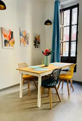 a dining room table with chairs and a vase of flowers at Mediterranean Flat next to the Historic Center in Valencia