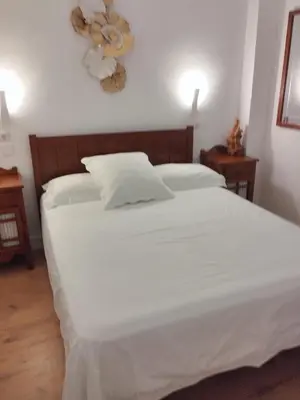 a bedroom with a white bed with two night stands at APARTAMENTO Claudia FARO in Faro de Cullera