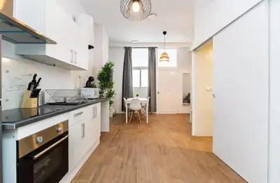 a kitchen with white cabinets and a wooden floor at Nuevo acogedor cerca del Centro in Valencia
