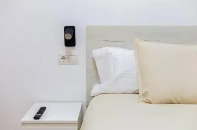 a white bed with a phone on a table next to it at Nuevo acogedor cerca del Centro in Valencia