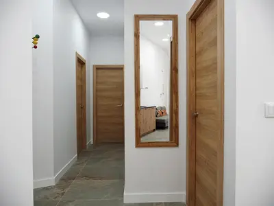 a hallway with a mirror and a wooden door at Apartamentos SAN JOSÉ in El Puig