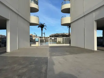 a view of a building with a palm tree in the background at Gran Canet, sea view 2beds in Canet de Berenguer