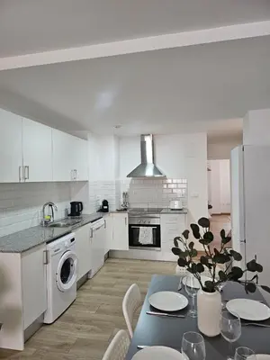 a kitchen with a table and a kitchen with white cabinets at Chic Escape Apartment in Godella