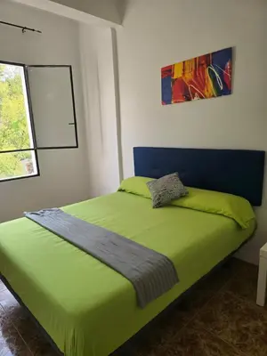 a bedroom with a green bed with a blue headboard at Habitaciones La Estación in Algemesí