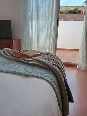 a bedroom with a bed with a book on it at Valencia Casa Rosa in Sedaví