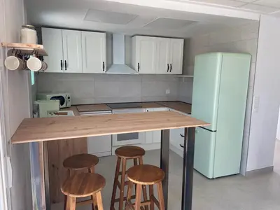 a kitchen with a counter with stools and a refrigerator at Villatella in Burriana