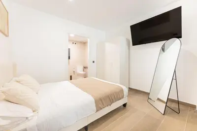 a white bedroom with a bed and a flat screen tv at Loft Urban Beach - Cerca del Mar in Valencia