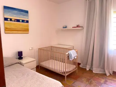 a baby crib in a bedroom with a painting at Villa con barbacoa para familias in Mareny Blau