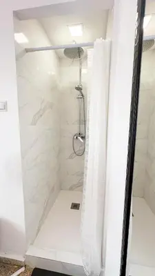 a shower with white marble walls and a shower curtain at Kmilo in Valencia
