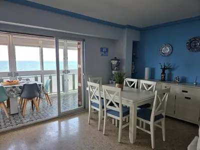 a kitchen and dining room with a white table and chairs at Ca Ulises Frente al mar, pensado para desconectar in Valencia