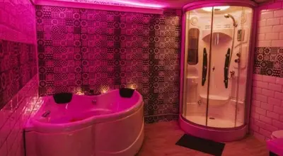 a pink bathroom with a tub and a shower at Bonita casa cueva con jacuzzi in Paterna