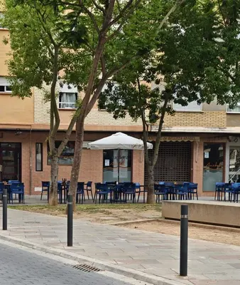 a building with tables and chairs in front of a building at Habitación Manises Aeropuerto in Manises