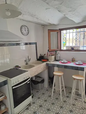 a kitchen with a sink and a counter with stools at El Cap de Pedra in Calles