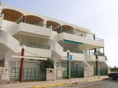 a large white building with a parking lot at Primer piso de 2 habitaciones en unifamiliar frente al mar in El Brosquil