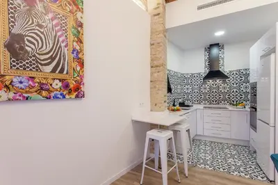 a kitchen with white cabinets and a painting on the wall at Apartment Ruzafa Tomasos in Valencia