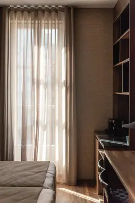 a bedroom with a bed and a window with curtains at Blanq Gran vía in Valencia