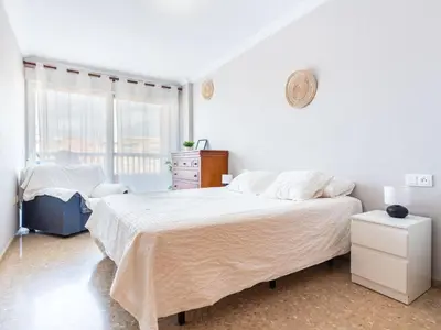 a white bedroom with a large bed and a window at Apartment Playa Patacona by Interhome in Valencia