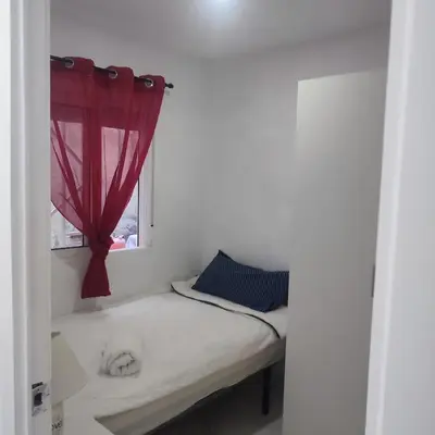 a small bed with a window with a red curtain at Rooms Ciudad Bella in Valencia