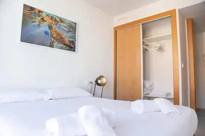 a bedroom with a bed with white sheets and a mirror at VLC Host - Cuber Apartments in Valencia