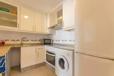 a kitchen with white cabinets and a washer and dryer at Tu refugio moderno en Valencia - piscina, gimnasio y padel incluidos in Valencia