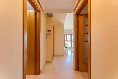 a hallway with wooden doors and a room with a floor at Tu refugio moderno en Valencia - piscina, gimnasio y padel incluidos in Valencia
