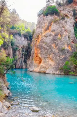 a river with blue water and a rocky cliff at Estudio Finca Mas el Bravo in Caudiel