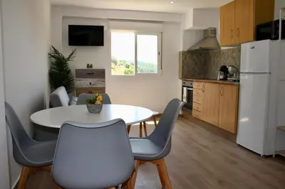 a kitchen with a table and chairs and a white refrigerator at Estudio Finca Mas el Bravo in Caudiel