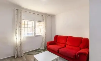 a red couch in a living room with a window at Encanto de Valencia in Cuart de Poblet