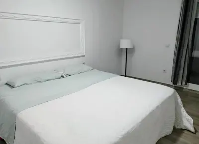 a white bed in a white bedroom with a window at Encanto de Valencia in Cuart de Poblet