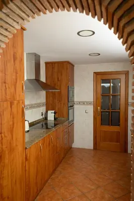 a large kitchen with wooden cabinets and a door at Your Paradise with Pool - 2 min from Beach in Moncófar