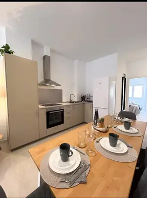 a kitchen with a wooden table with plates and wine glasses at Hermoso apartamento en Nazaret in Valencia