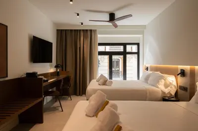 a hotel room with two beds and a desk at Moontels Colón in Valencia