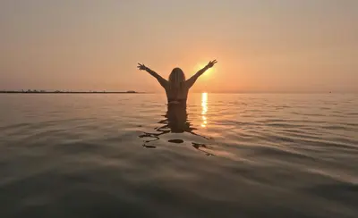 a woman standing in the water at sunset at Apartmento en 5 Mares in Puebla de Farnals