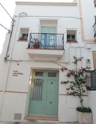 a white building with a green door and a balcony at Casa Albacora 1892 in Losa del Obispo
