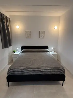 a bedroom with a bed with two nightstands and two lights at K&A Apartments in Valencia