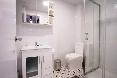 a white bathroom with a toilet and a sink at Window to Central Market in Valencia