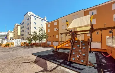 a playground in a parking lot next to a building at Stunning Apartment In Moncofa With Swimming Pool in Moncófar