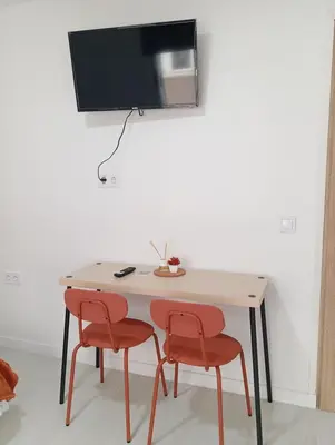 a table with two chairs and a television on a wall at Estudios Diego in Puerto de Sagunto