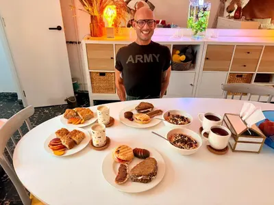 a man sitting at a table with plates of pastries at Habitación geniale cerca de Russafa in Valencia