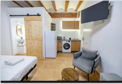 a room with a bed and a table and a refrigerator at Suite centro con cocina in Valencia