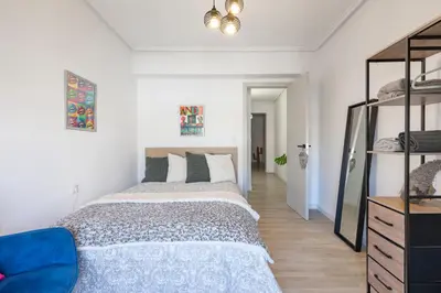 a bedroom with a large bed and a blue chair at Valencia Designer Apartment next to metro in Paterna