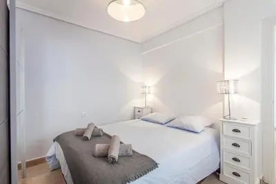 a white bedroom with a bed and a night stand at Valencia Flat Rental 3 bedroom in Extramurs in Valencia