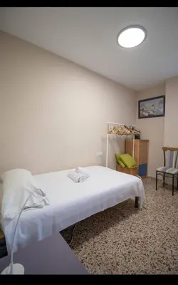 a bedroom with a white bed and a chair at Casa con vistas al rio in Navajas