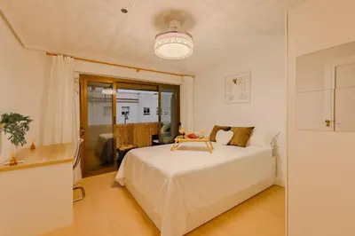 a white bedroom with a bed and a window at Cabañal BeachFront , 1 Min to Sea , AC , Coffee , Balcony , FastWifi in Valencia
