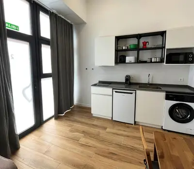 a kitchen with white cabinets and a wooden floor at Urban loft Benicalap in Valencia