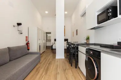 a living room with a couch and a kitchen at Urban loft Benicalap in Valencia