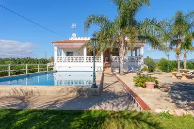 a white house with a swimming pool and palm trees at Masia Miliuca Paraíso rural a un paso de Valencia - Rural paradise close to Valencia in Bétera