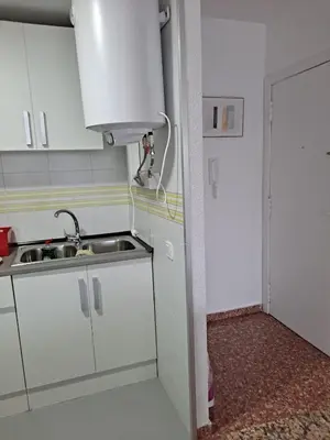 a small kitchen with white cabinets and a sink at Comfortable apartment in the Feria 2 area in Valencia