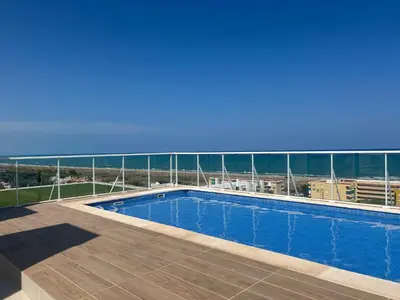 a swimming pool on top of a building with the ocean at Canet al Mar Luxe y Confort-Pet Friendly in Canet de Berenguer